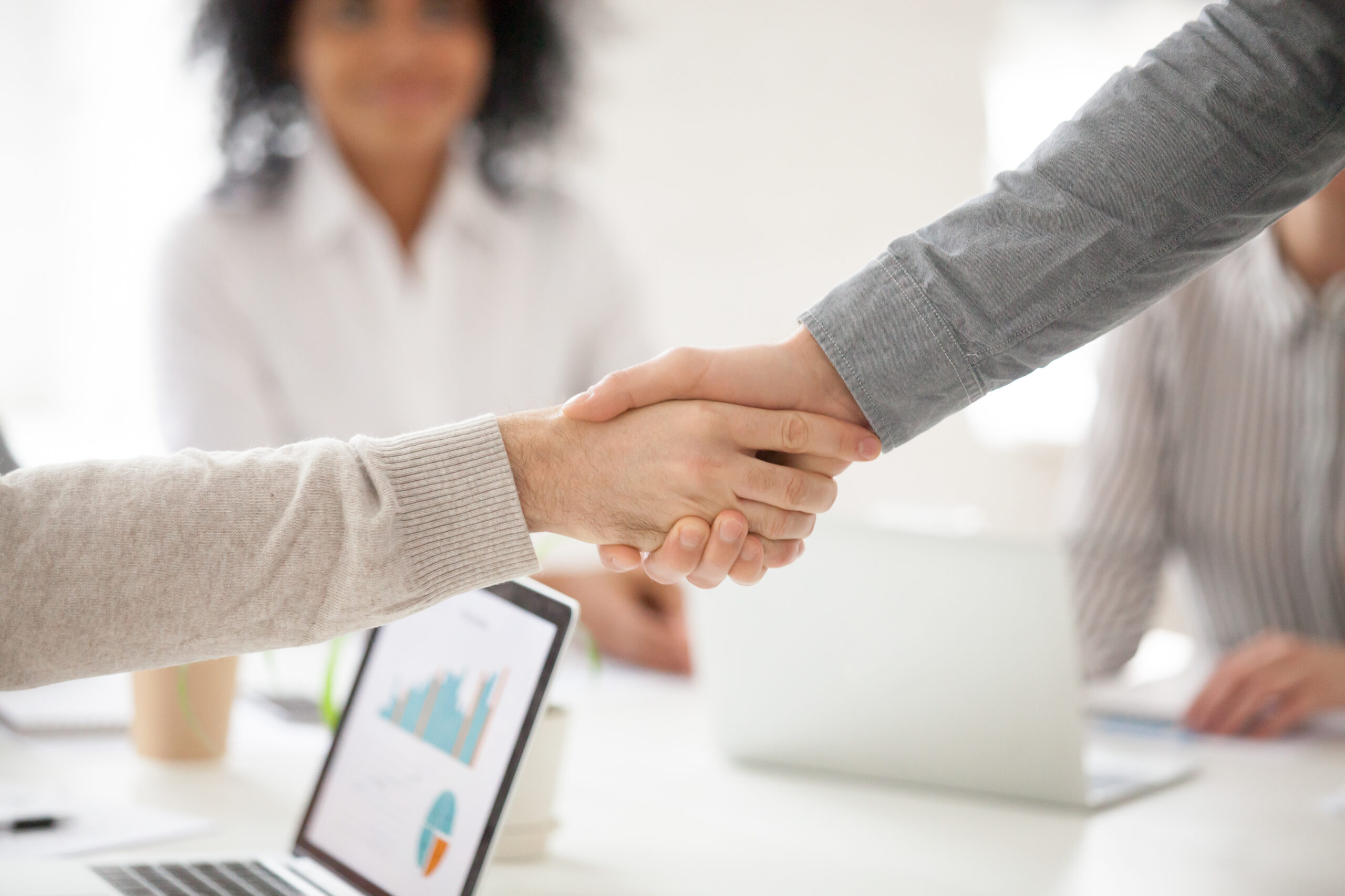 Business partners handshaking at group meeting making project in Two business partners handshake at group meeting making online project investment, male hands shake as concept of successful collaboration result or starting partnership after effective negotiations